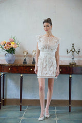 A white mini dress with floral embroidery and lace details showcasing a delicate and feminine design