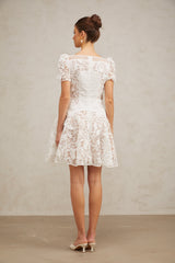 A white mini dress with floral lace pattern and puff sleeves featuring a romantic Josette design