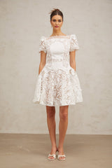 A white mini dress with floral lace pattern and puff sleeves named Josette