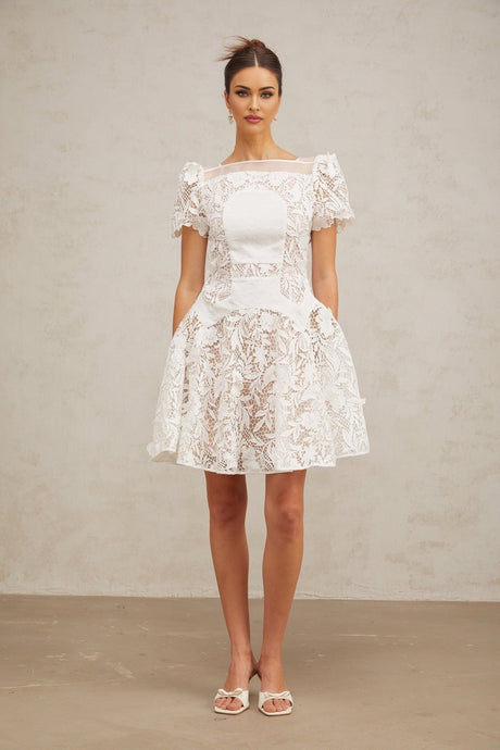A white mini dress with floral lace pattern and puff sleeves named Josette