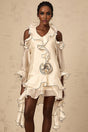 A white mini dress with flounce detailing and ribbon accents named Tiphaine