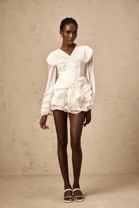 A white mini dress with full pleating and a cinched waist featuring a rosier style design