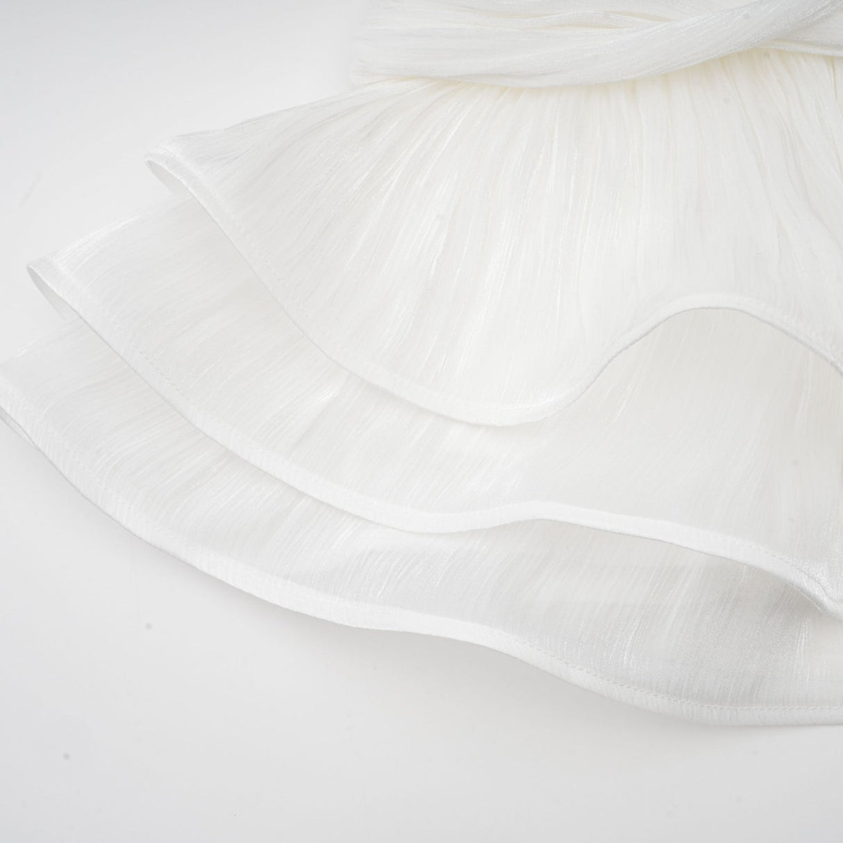 A white mini dress with full pleats and a cinched waist featuring a formfitting silhouette and short length