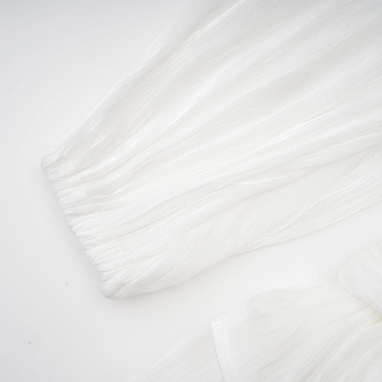 A white mini dress with full pleats and a cinched waist featuring a rosier design