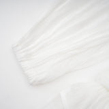 A white mini dress with full pleats and a cinched waist featuring a rosier design