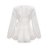 A white mini dress with full pleats and a cinched waist featuring a rosier design