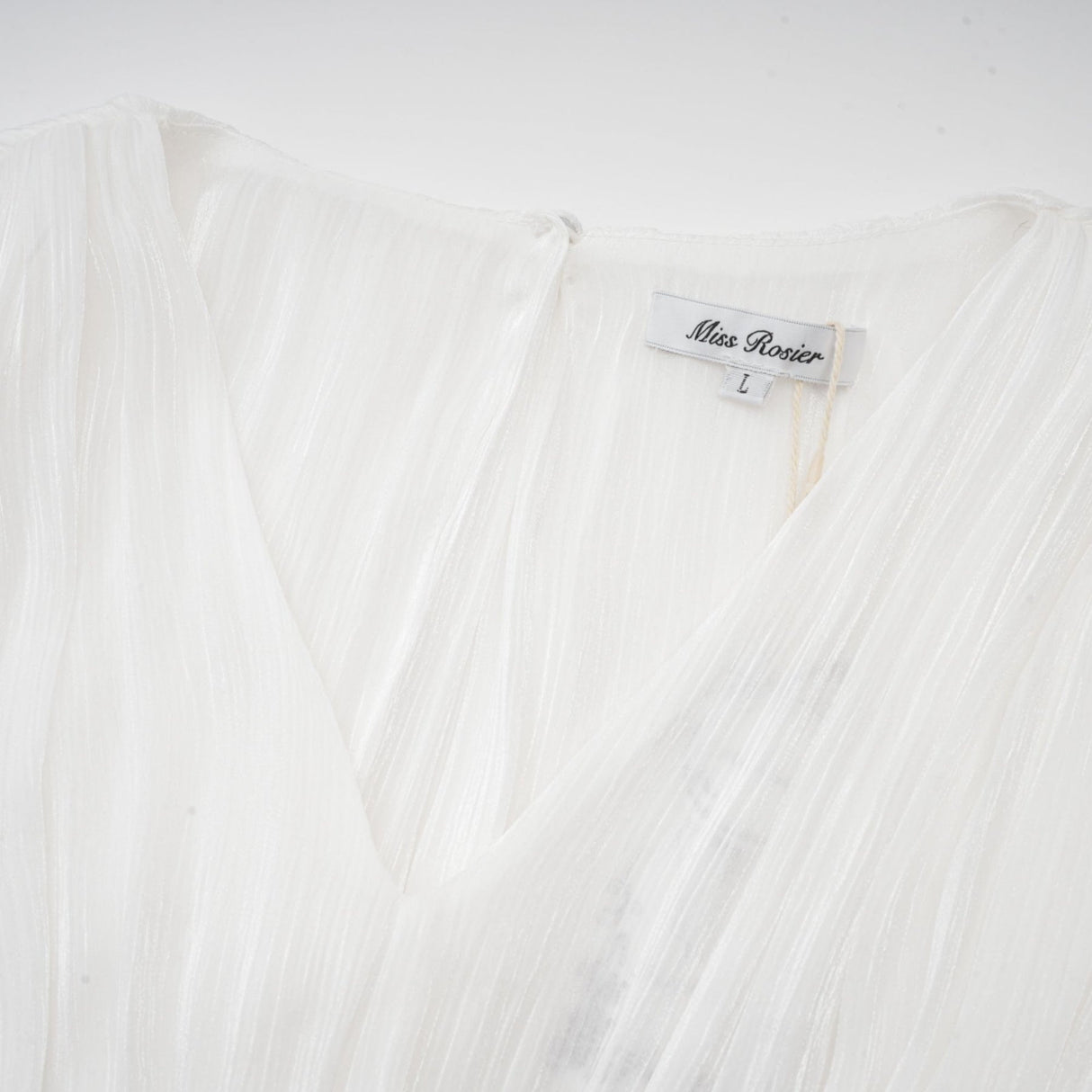 A white mini dress with full pleats and a cinched waist featuring a rosier design