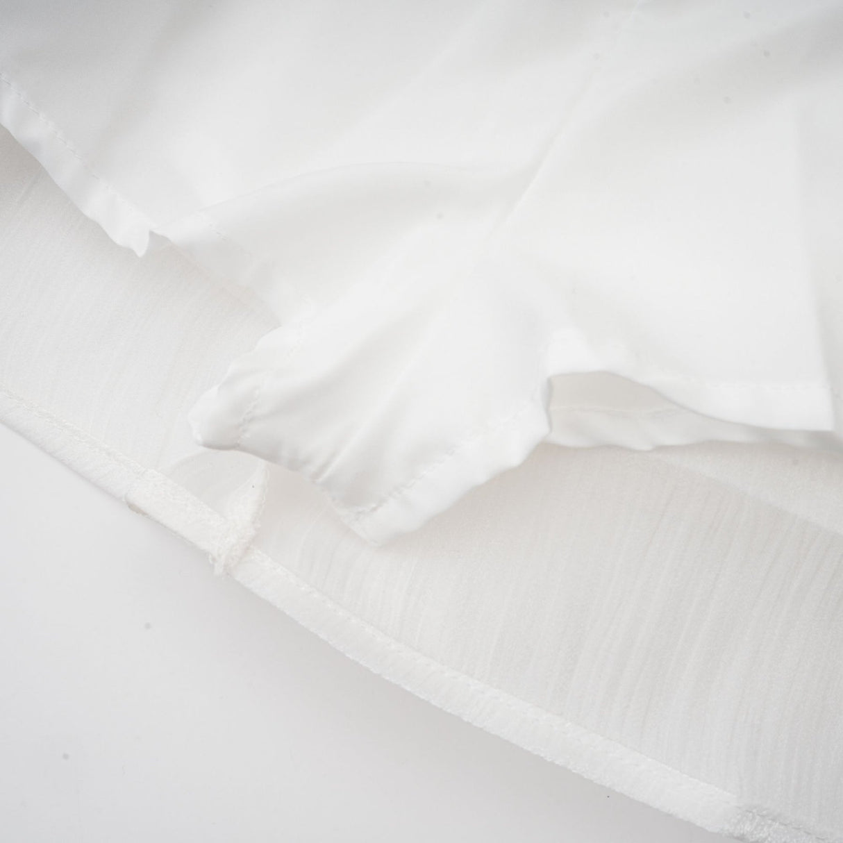 A white mini dress with full pleats and a cinched waist featuring a rosier design