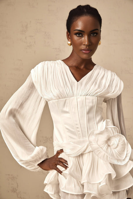 A white mini dress with full pleats and a cinched waist featuring a rosier style design