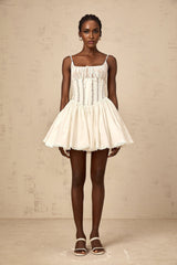 A white mini dress with lace details and a corset style bodice featuring a fitted silhouette and feminine design