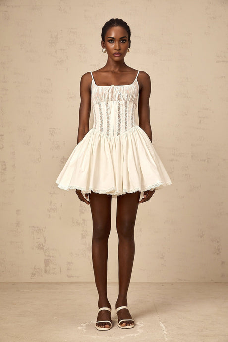 A white mini dress with lace details and a corset style bodice featuring a fitted silhouette and feminine design