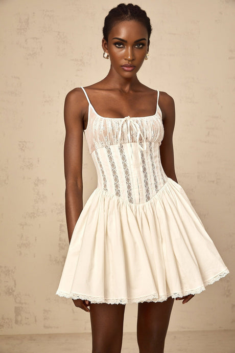 A white mini dress with lace details and a corsetstyle bodice featuring a fitted silhouette and delicate floral accents