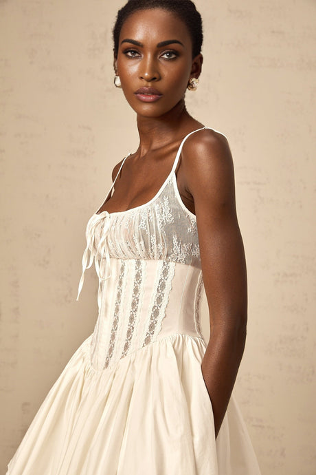 A white mini dress with lace details and a corsetstyle bodice featuring a fitted silhouette and short length