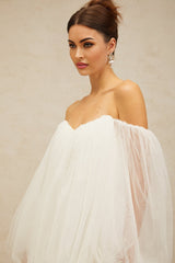 A white mini dress with layered bubble tulle skirt and sleeves worn by a model standing against a plain background