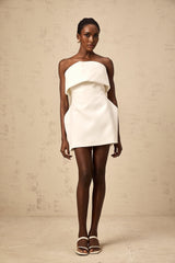 A white mini dress with offshoulder neckline and puff sleeves worn by a model against a plain background
