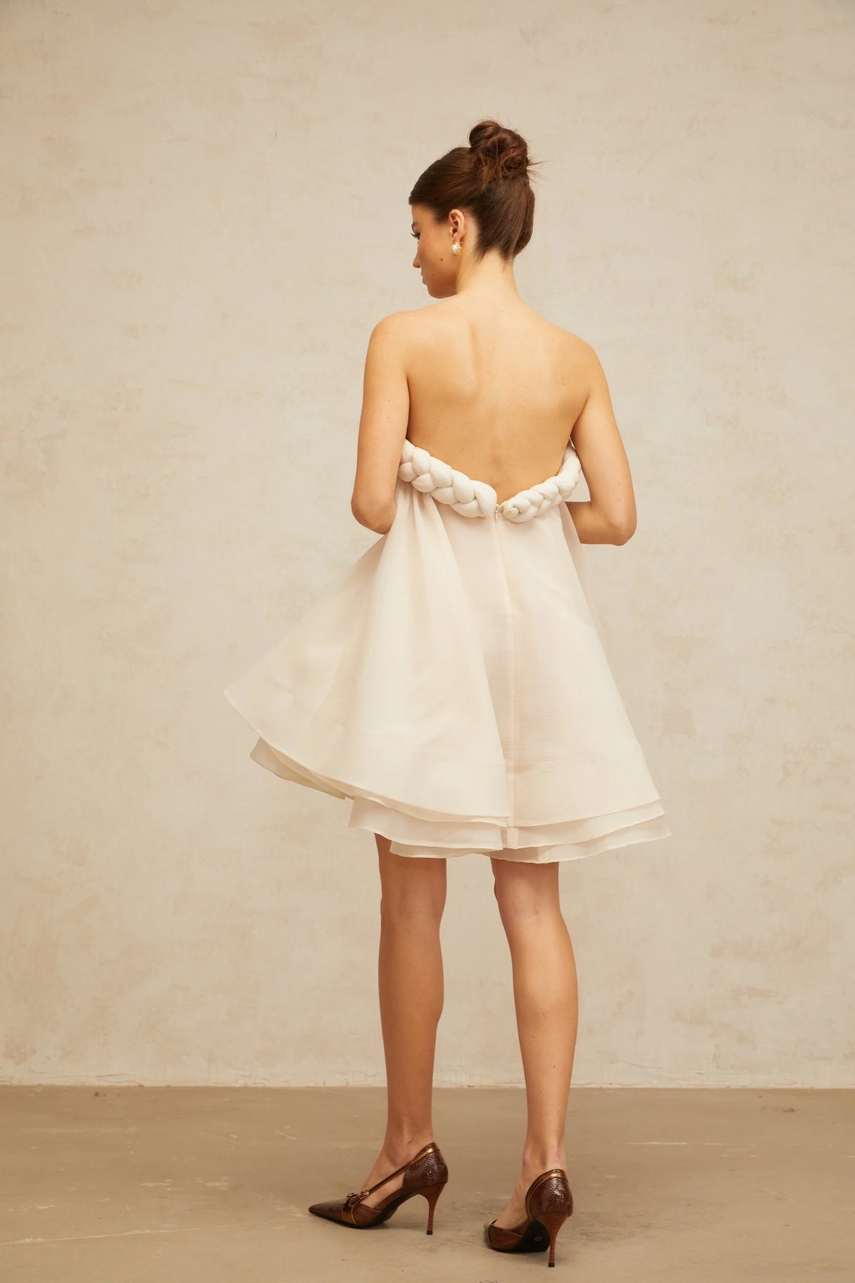A white mini dress with puff sleeves and braided details featuring a short hemline and a feminine silhouette