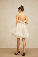 A white mini dress with puff sleeves and braided details featuring a short hemline and a feminine silhouette