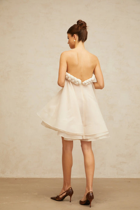 A white mini dress with puff sleeves and braided details featuring a short hemline and a feminine silhouette