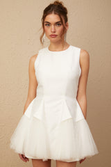 A white mini dress with puff sleeves and tulle panels featuring a fitted bodice and flared skirt
