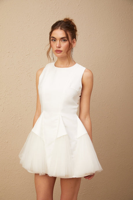 A white mini dress with puff sleeves and tulle panels showcasing a feminine silhouette