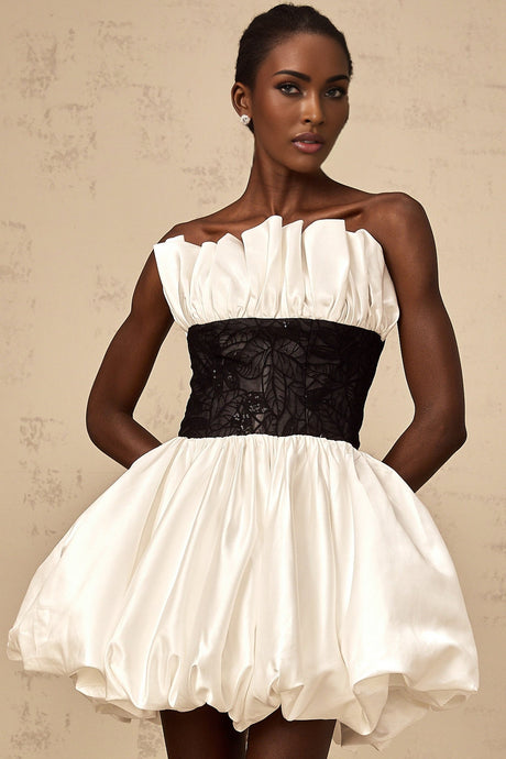 A white mini dress with puff sleeves featuring lace paneling and a satin finish