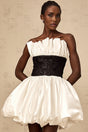 A white mini dress with puff sleeves featuring lace paneling and a satin finish