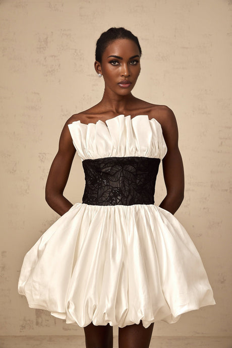 A white mini dress with puff sleeves featuring lace panels and a satin fabric