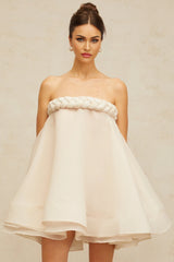 A white mini dress with puffed sleeves and braided detailing named Violette