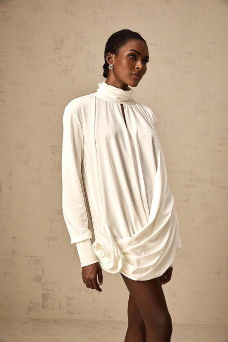 A white mini dress with ruched detailing and faux flower embellishments called the Maeva dress