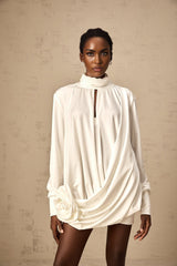 A white mini dress with ruched detailing and faux flower embellishments called the Maeva dress