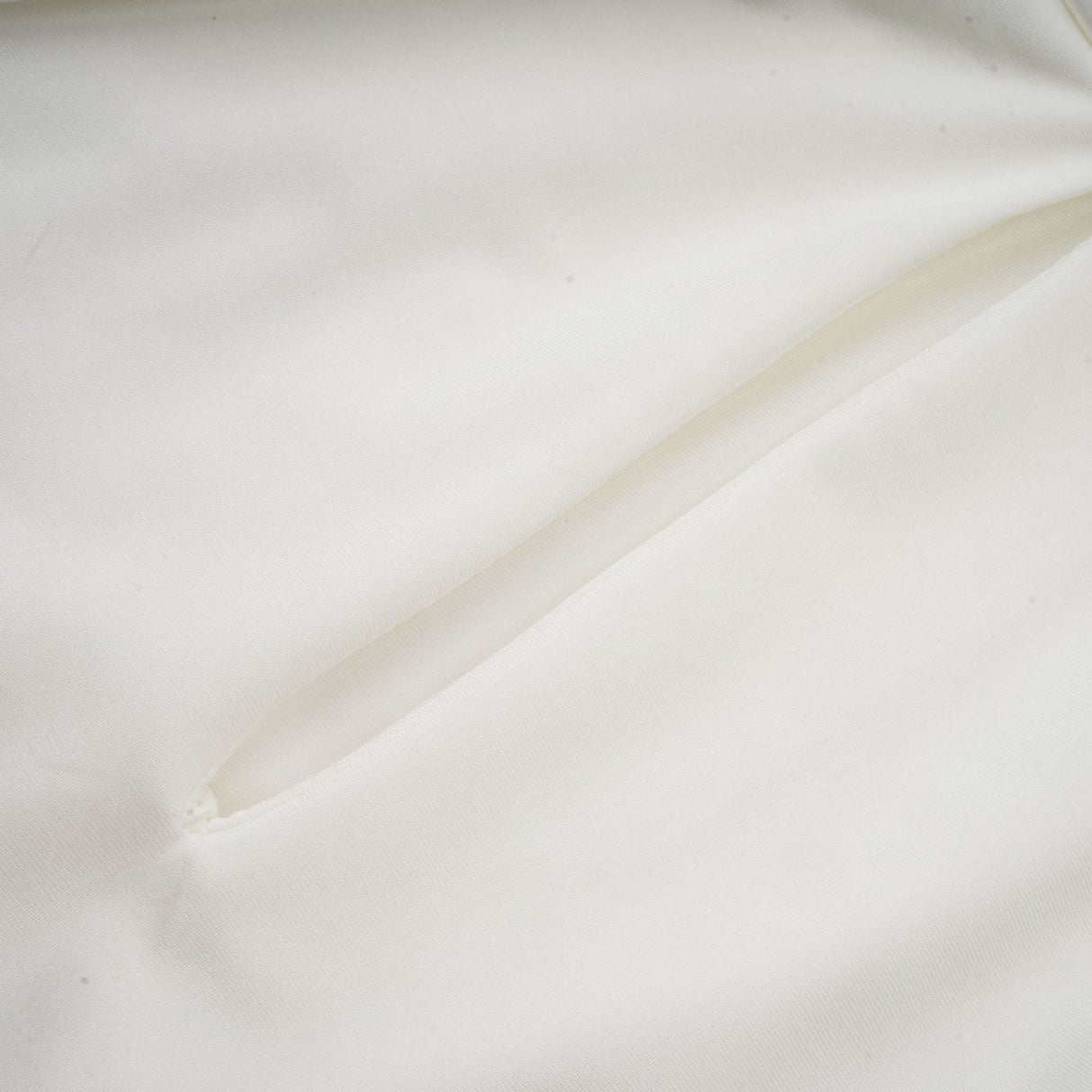 A white mini dress with ruched detailing and faux flower embellishments called the Maeva dress