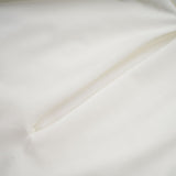 A white mini dress with ruched detailing and faux flower embellishments called the Maeva dress