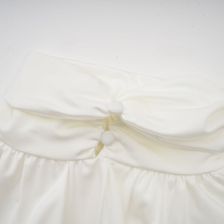 A white mini dress with ruched detailing and faux flower embellishments featuring a short hemline and formfitting silhouette