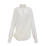 A white mini dress with ruched detailing and faux flower embellishments on a female model