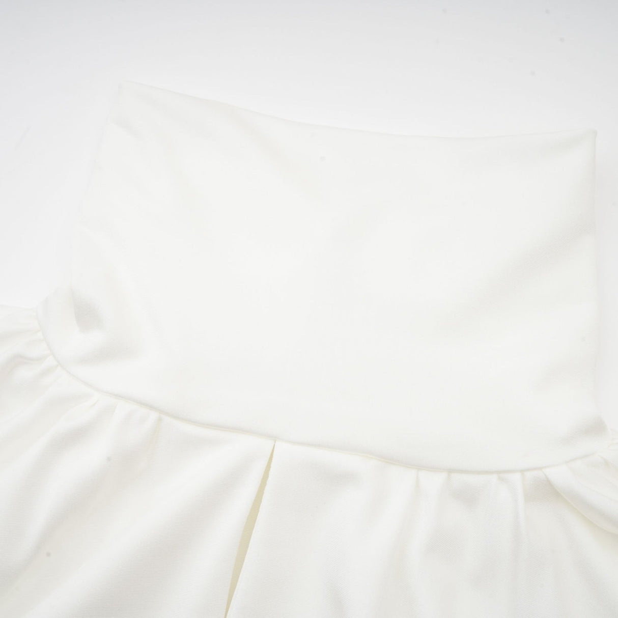 A white mini dress with ruched detailing and faux flower embellishments showcasing the Maeva design