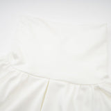 A white mini dress with ruched detailing and faux flower embellishments showcasing the Maeva design