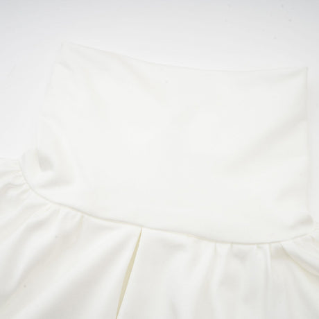 A white mini dress with ruched detailing and faux flower embellishments showcasing the Maeva design