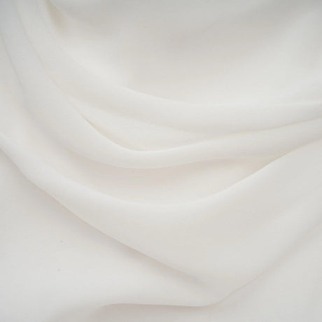 A white mini dress with ruched detailing and ribbon design accents featuring a fitted silhouette and short length