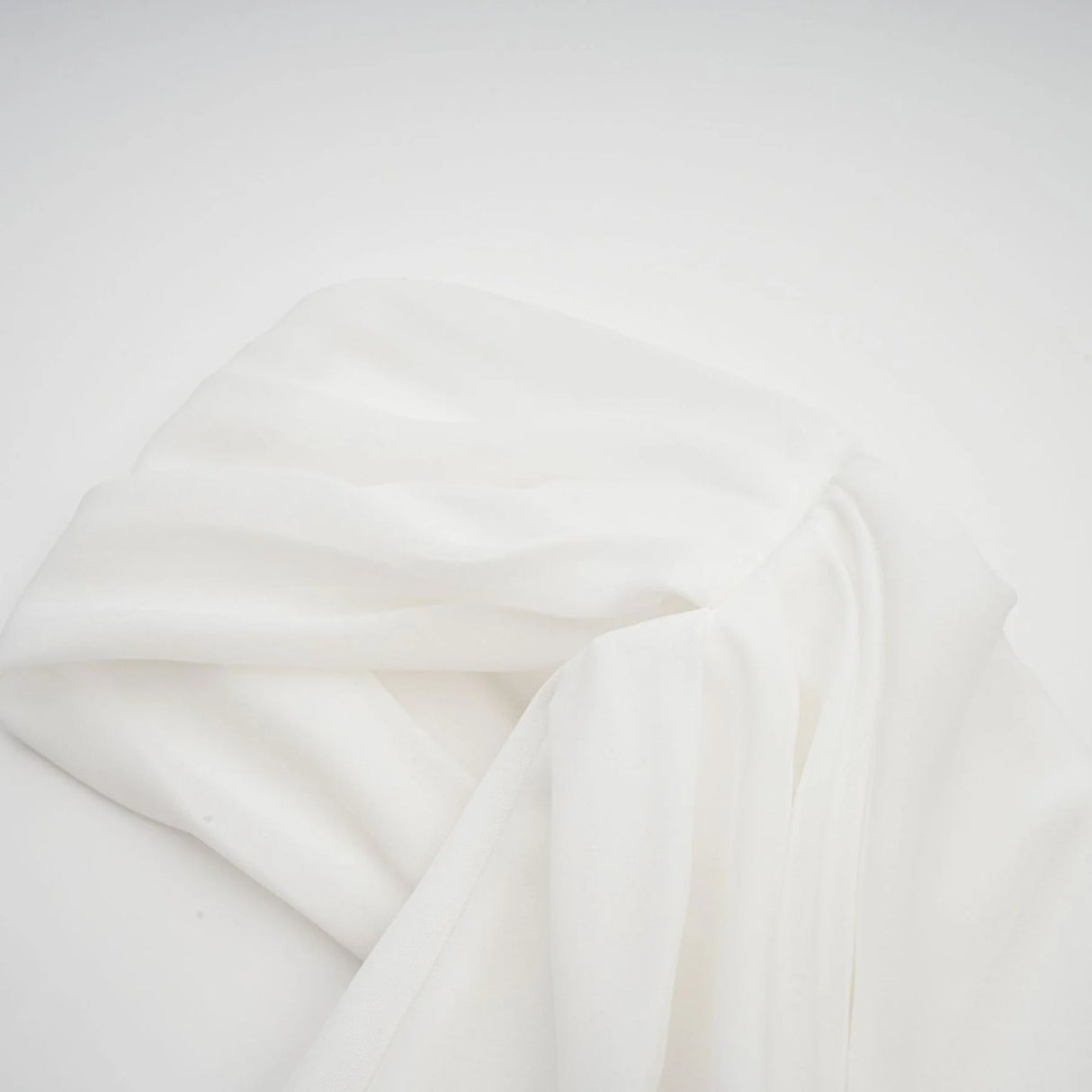 A white mini dress with ruched fabric and ribbon design details featuring a short hemline and fitted silhouette