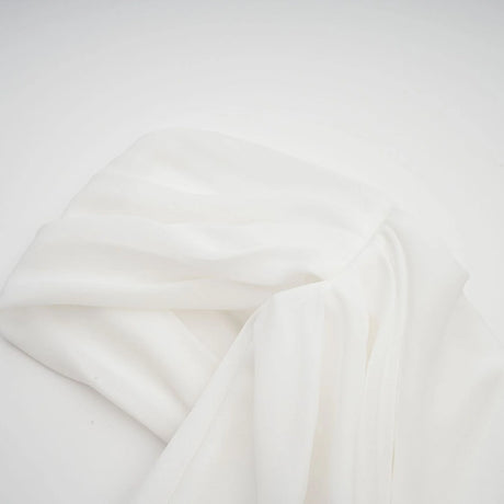 A white mini dress with ruched fabric and ribbon design details featuring a short hemline and fitted silhouette
