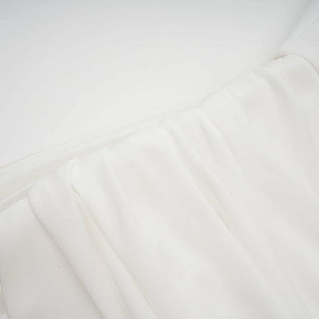 A white mini dress with ruched fabric and ribbon design details featuring a short hemline and fitted silhouette