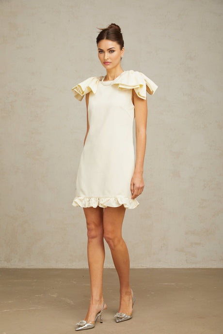 A white mini dress with ruffles and a bow detail named Constance