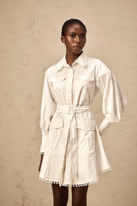 A white mini shirt dress with a belt cinched at the waist featuring short sleeves and a collar