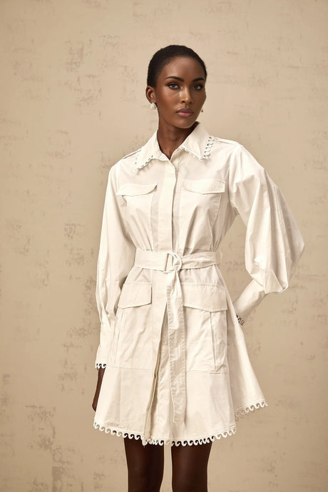 A white mini shirt dress with a belt cinched at the waist featuring short sleeves and a collar