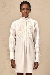 A white mini shirt dress with lace trim and ruffled details featuring a collared neckline and short sleeves