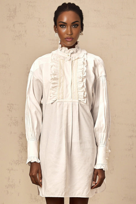 A white mini shirt dress with lace trim and ruffled details featuring a collared neckline and short sleeves