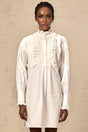 A white mini shirt dress with lace trim and ruffled details featuring a collared neckline and short sleeves