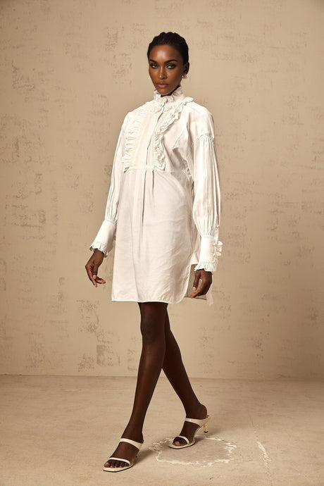 A white mini shirt dress with lace trim and ruffled details short sleeves and a collar