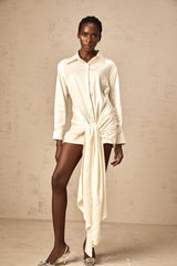 A white mini shirt dress with ruched detailing and ribbon accents named Daphne featuring a short length and buttonup front