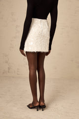 A white mini skirt covered in shimmering sequins